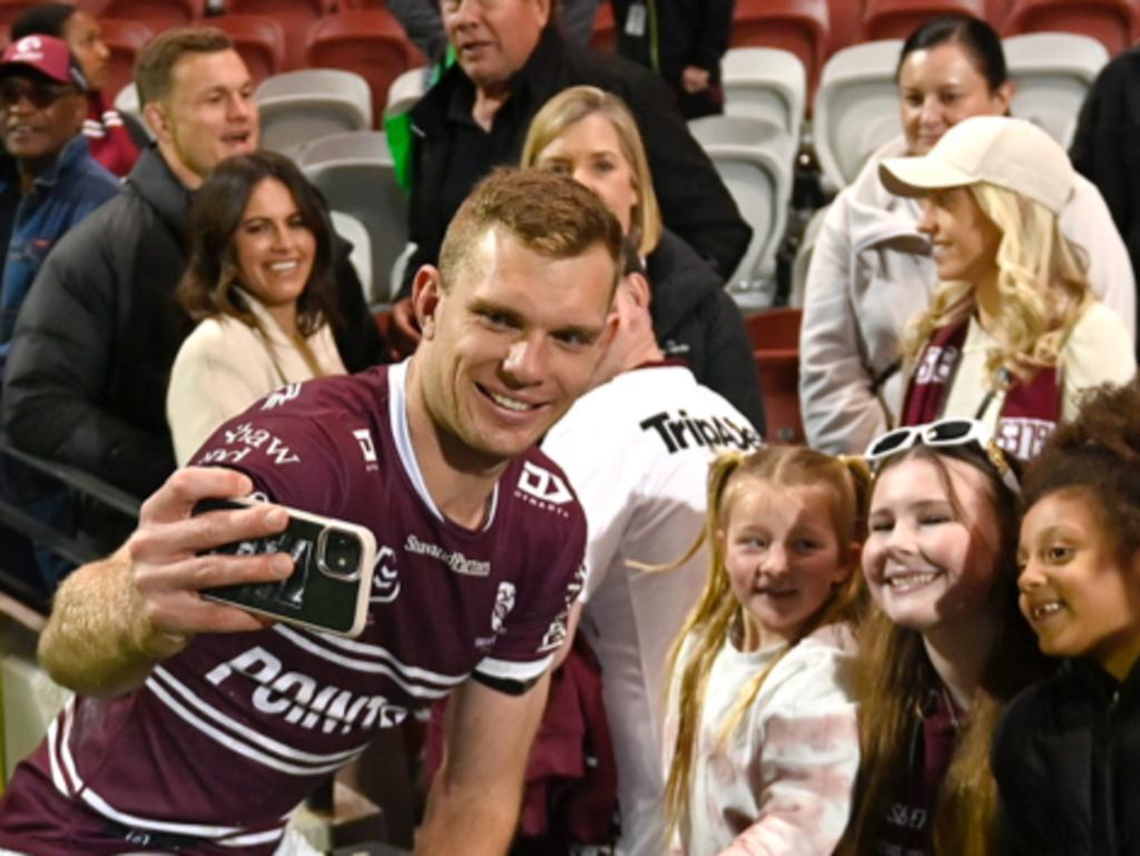 Name these photobombers: NRL's newest glamour couple Liam Knight and Danika Mason can be seen in the background as Tom Trbojevic poses with some fans. Credit: Supplied.