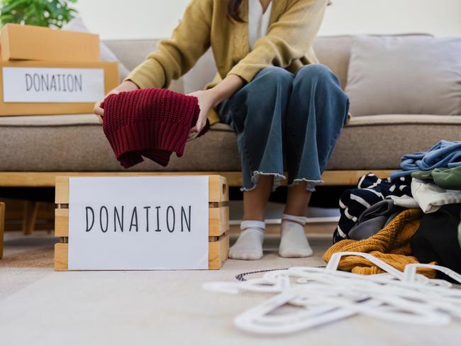 Young Asian women sit in living room sorting clothes for donation in a donation box second hand clothes. Donate concept.