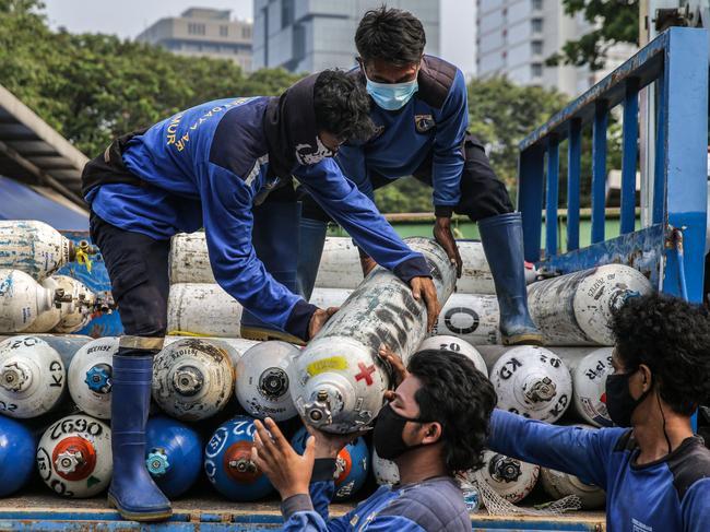 Workers unload tanks at an emergency oxygen station in Jakarta on July 5. Indonesia’s death rate has spiked as the delta variant tears through the country. Picture: Mariana/AFP