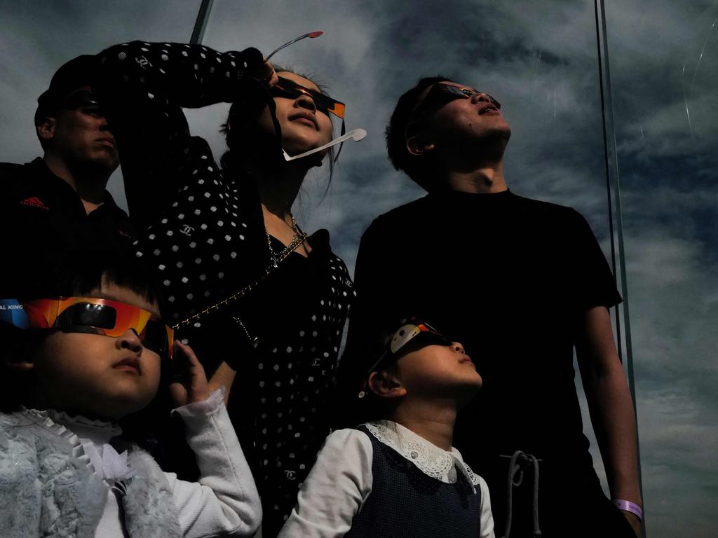 A family look toward the sky at the 'Edge at Hudson Yards' observation deck during a total solar eclipse across North America. Picture: AFP