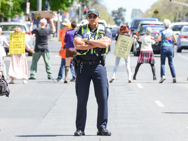 A police officer stands guard behind the Nutbushing climate rebels. Picture: AAP Image/Brenton Edwards