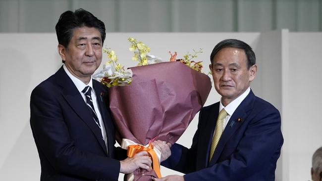 Chief Cabinet Secretary Yoshihide Suga, right, presents flowers to Japan's Prime Minister Shinzo Abe after Suga. Picture: Getty