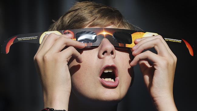 FILE - In this Wednesday, Aug. 16, 2017 photo, Colton Hammer tries out his new eclipse glasses he just bought from the Clark Planetarium in Salt Lake City in preparation for the Aug. 21 eclipse. Eye doctors urge strict adult supervision for eclipse watchers under 16 years old.  (Scott G Winterton/The Deseret News via AP)