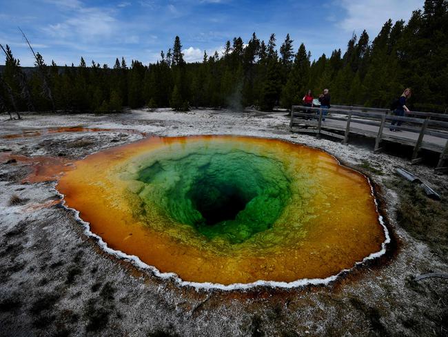 (FILES) In this file photo taken on May 13, 2016 tourists view the Morning Glory hot spring in the Upper Geyser Basin of Yellowstone National Park in Wyoming. - The US Senate approved a landmark expansion of protected lands on February 12, 2019, the first major gain for conservationists in two years after repeated setbacks by the Trump administration. The Senate voted 98-2 in support of the Natural Resources Management Act, which gives new or strengthened protection from mining and encroachment to more than two million acres (810,000 hectares), expands eight national parks and historic sights, and adds new national monuments and heritage areas. (Photo by Mark Ralston / AFP)