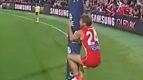 Dane Rampe climbs the goalpost as Essendon’s David Myers takes a shot for goal.