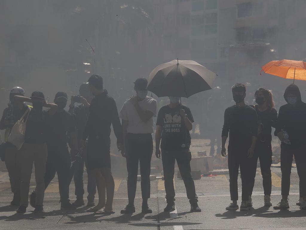 Protesters form a line as smoke from burning debris fill a street. Kin Cheun/AP