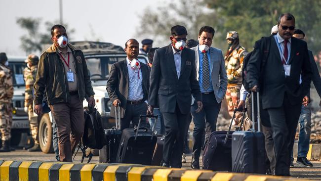 Indian nationals evacuated from the Chinese city of Wuhan, following the coronavirus outbreak, wear facemasks as they carry their belongings on a road at Indira Gandhi International Airport in New Delhi. Picture: AFP