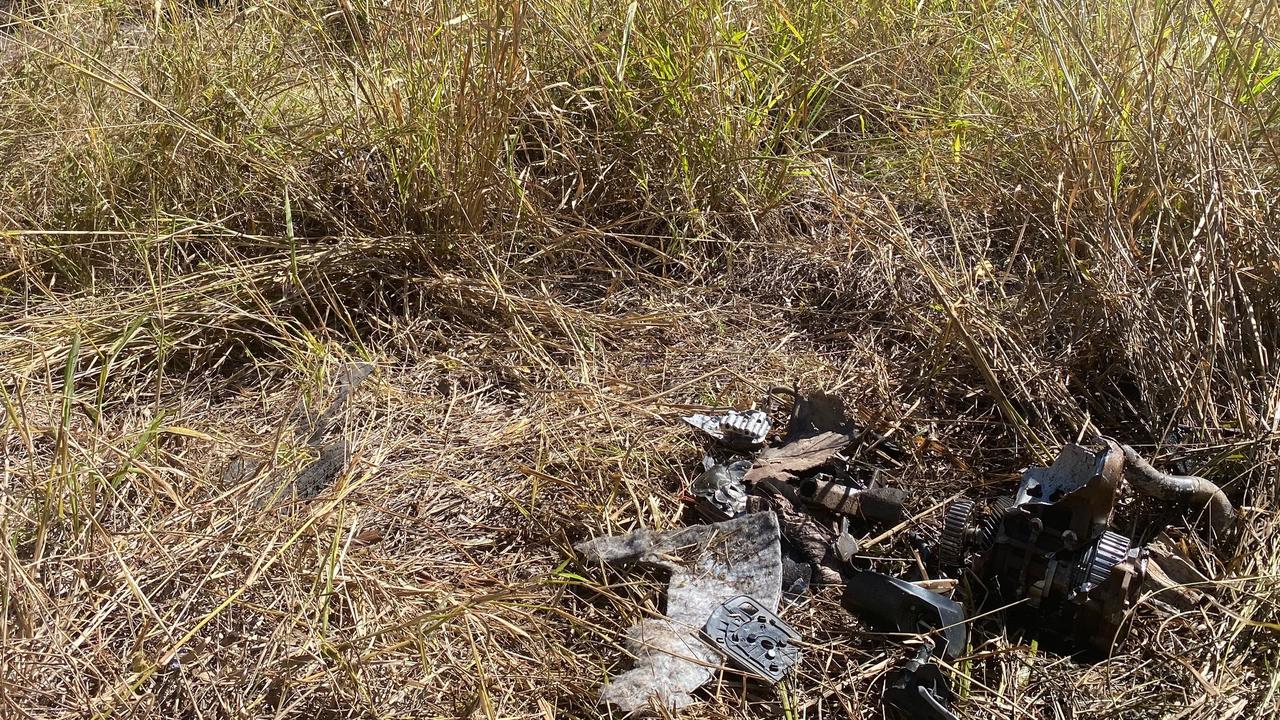 The mowed down grass just before the pool of scorched earth where the SUV came to a rest, with car parts scattered in the grass.