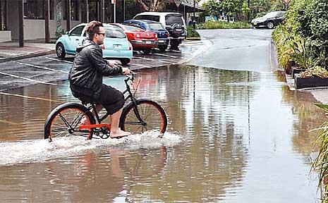 A keen cyclist makes his way through flooding at Byron Bay after the town copped a massive morning shower. Picture: Greg Cromwell