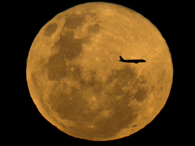 An aircraft flies past the full moon last night. Picture: Jay Town