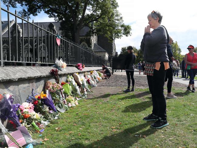 A woman prays after placing flowers. New Zealand is reeling after a terrorist attack in Christchurch. Picture Gary Ramage