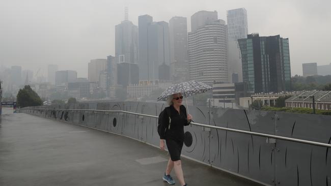 A woman walks in the haze and drizzle. Picture: David Crosling