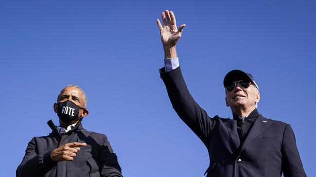 Former president Barack Obama and Democratic presidential nominee Joe Biden wave to the crowd at the end of a drive-in campaign rally at Northwestern High School in Flint, Michigan, on Saturday.