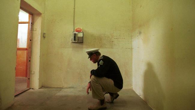 A police officer crouches in the now-infamous Snowtown bank vault May, 1999. Photo: Grant Turner. South Australia / Crime