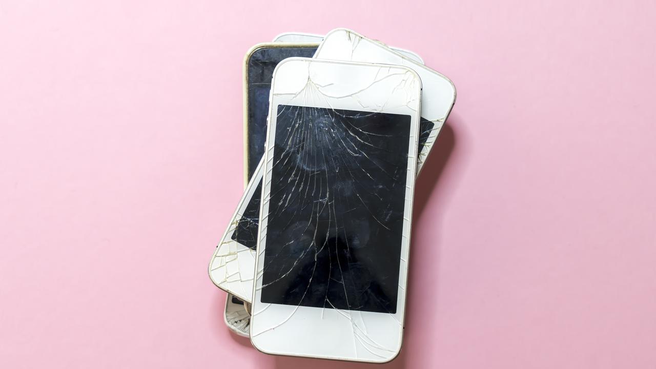 pile of old broken mobile phones with pink background