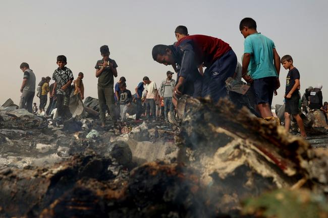 Palestinians gather at a Rafah displacement camp hit by an Israeli strike