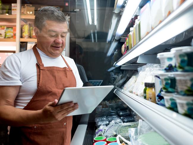 Happy man working at a grocery store doing the inventory - small business concepts