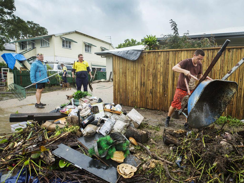 Clinton Smith empties another wheelbarrow of waste from his flood damaged property at Hermit Park. Picture: Lachie Millard