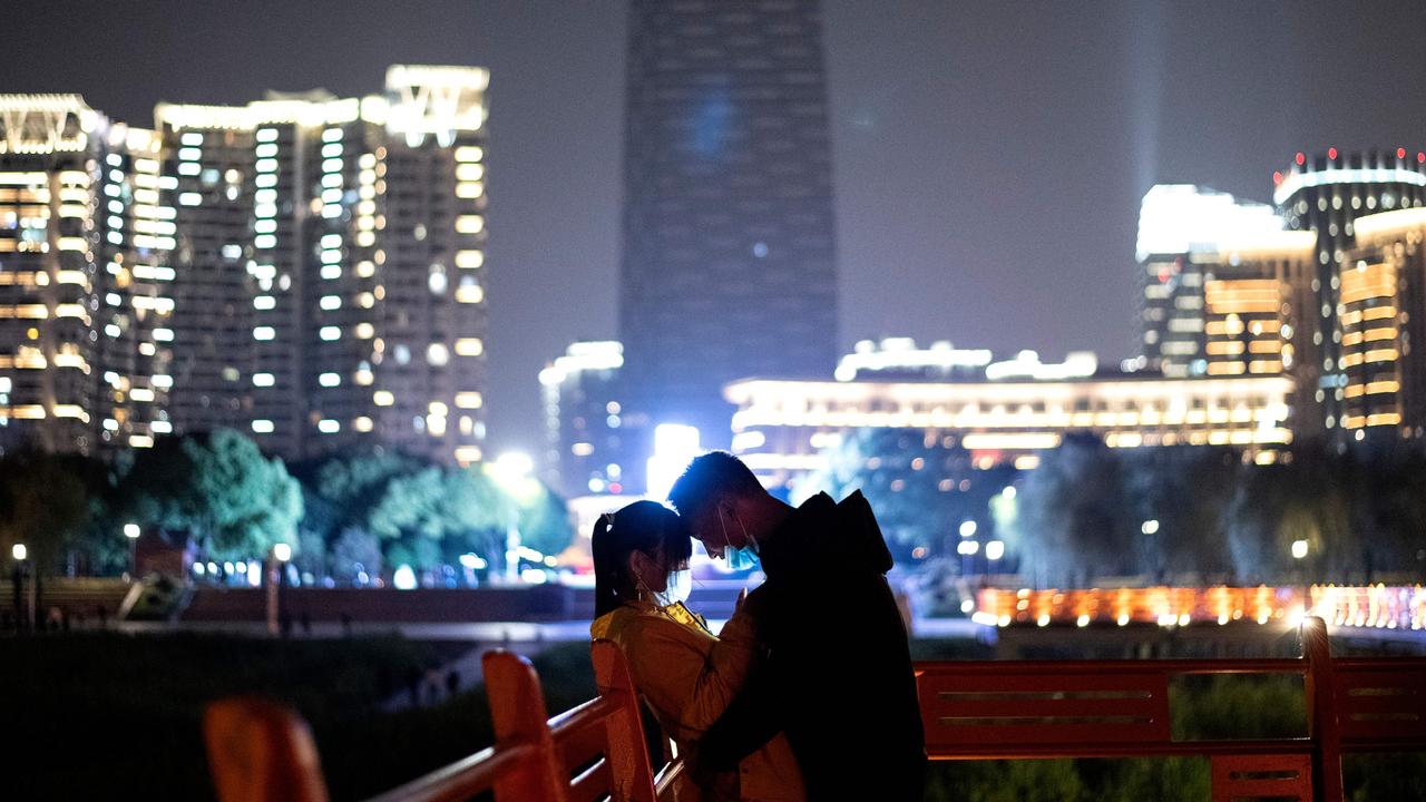 A couple wearing a face mask cuddle along a park at the Yangtze river in Wuhan in China's central Hubei province early on April 12, 2020. Picture: Noel Celis/AFP