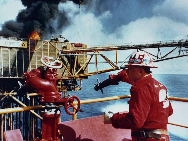 10/07/1988. Fire fighting specialist Paul "Red" Adair aboard the support vessel Tharos off of northeast Scotland, where he was fighting a fire on the oil platform Piper Alpha, seen still in flames in background.  Adair, a world-renowned oil well firefighter who revolutionized the science of capping exploding and burning wells,  died Saturday, July 7, 2004 in Houston, Texas, his daughter said. He was 89. (AP Photo, File)