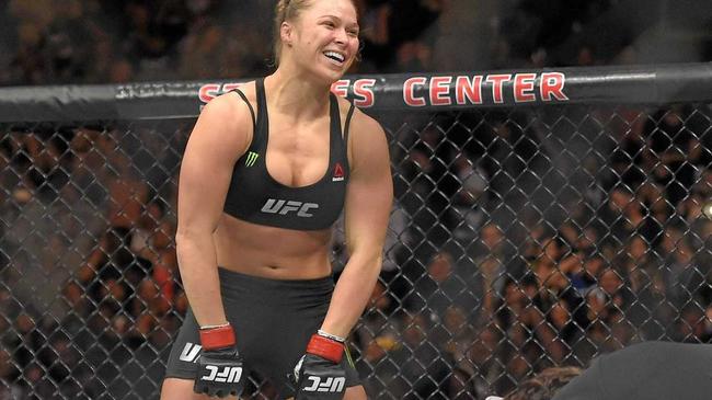 BIG NAME: Ronda Rousey, top, celebrates as Cat Zingano kneels on the mat during a UFC 184 mixed martial arts bantamweight title bout. Picture: Mark J. Terrill-AAP