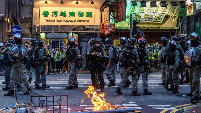 Police walk past a burning barricade set up by protesters during a rally against the new national security law in Hong Kong. Picture: Anthony Wallace/AFP