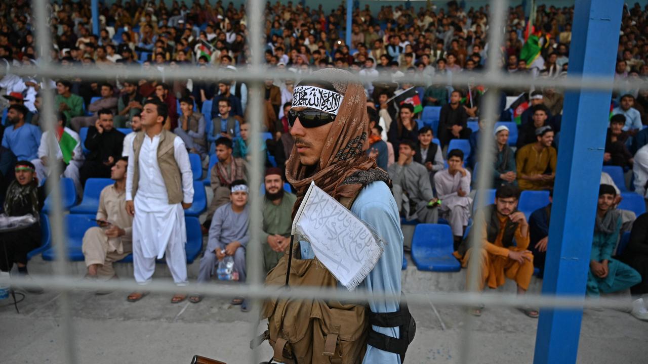 A Taliban fighter (C) keeps vigil as spectators watch the Twenty20 cricket trial match being played between two Afghan teams 'Peace Defenders' and 'Peace Heroes' at the Kabul International Cricket Stadium. Picture: AFP