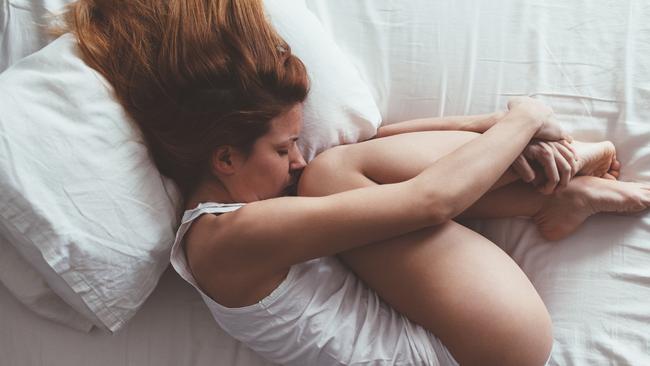 Young woman lying down in foetal position.