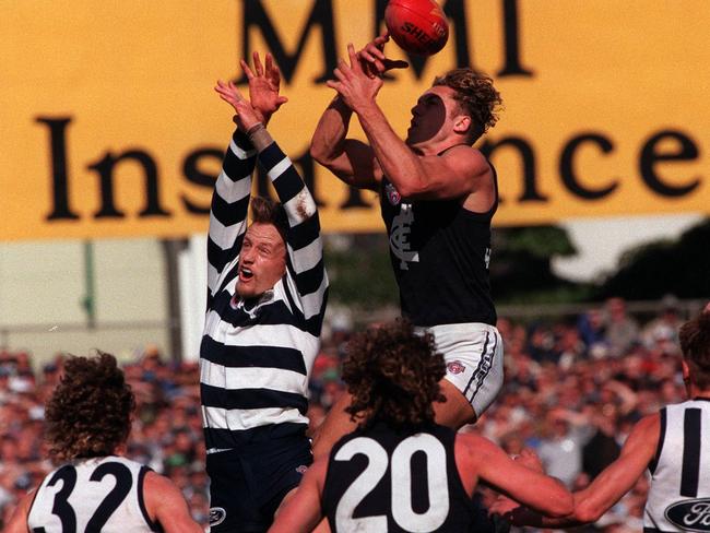 Anthony Koutoufides leaps over John Barnes at Kardinia Park in 1996.