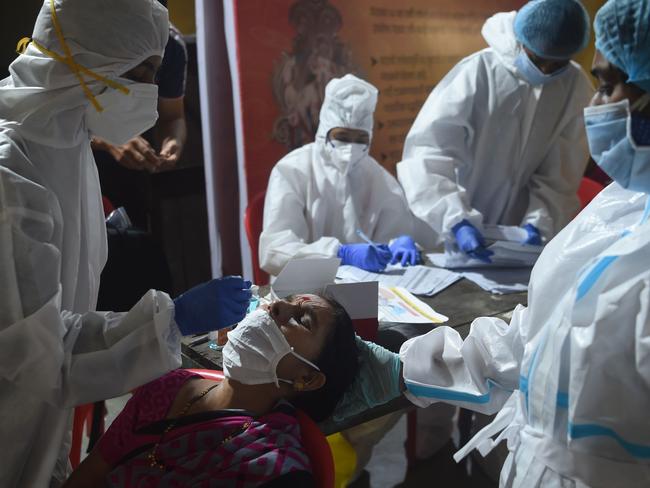 A health worker wearing protective gear collects a swab sample during medical screening for COVID-19 in Mumbai. Picture: AFP.