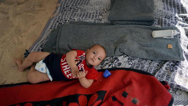 A Palestinian baby lies on blankets placed on the sand under the shade of a tent as summer temperatures reach over 30 degrees. Picture: AFP