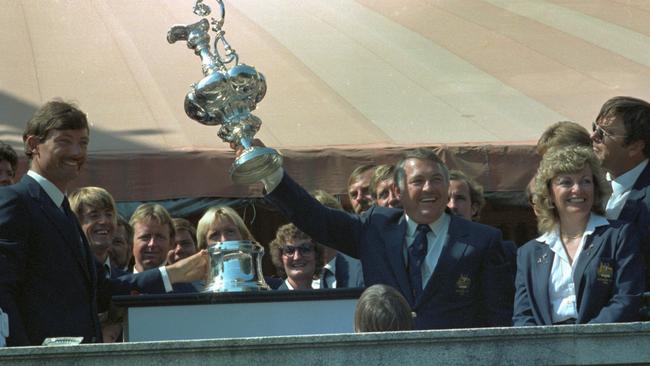 Alan Bond holds up the America's Cup watched on by John Bertrand, left, after Australia II defeated the United States contestant Liberty.