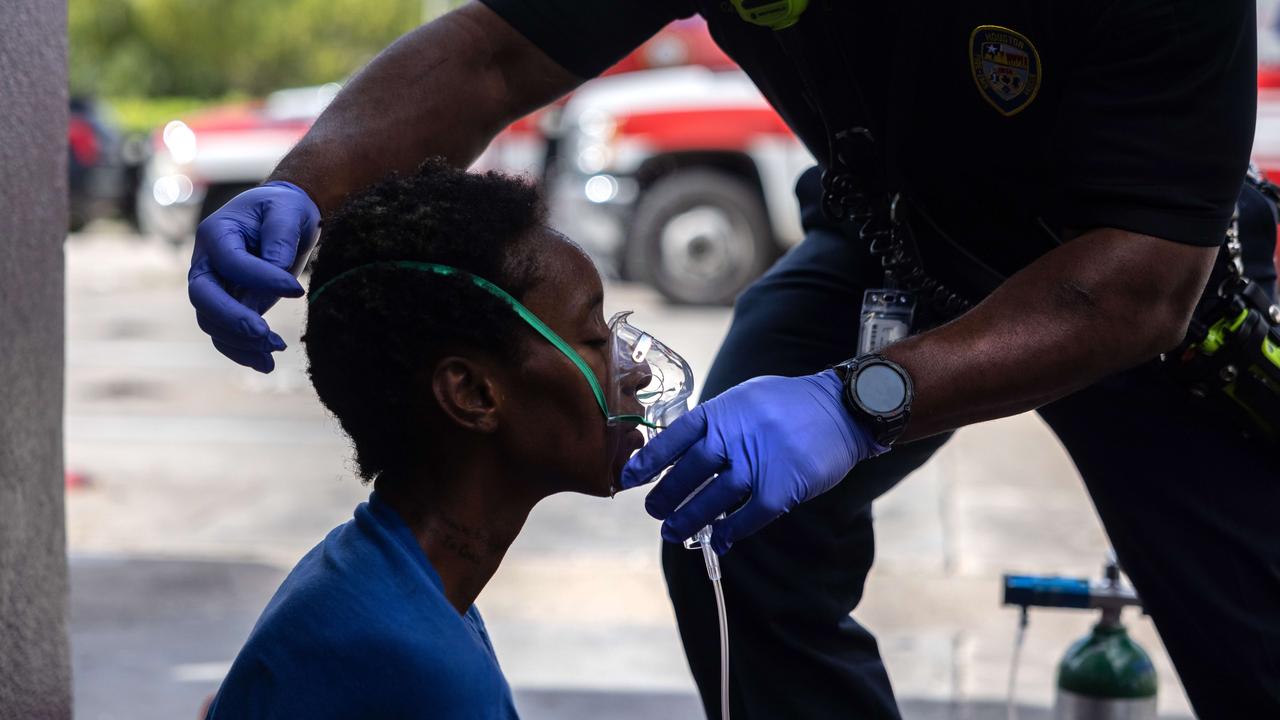 Houston Fire Department EMS supervisor Michael Norwood gives oxygen to a woman with suspected Covid-19 before transporting her to a hospital. Picture: John Moore/Getty