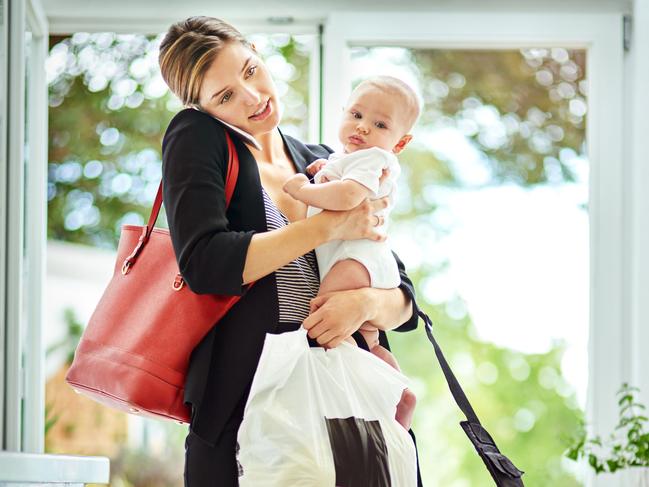 Shot of a busy businesswoman carrying groceries and her baby while talking on the phone on her return from work. iStock image