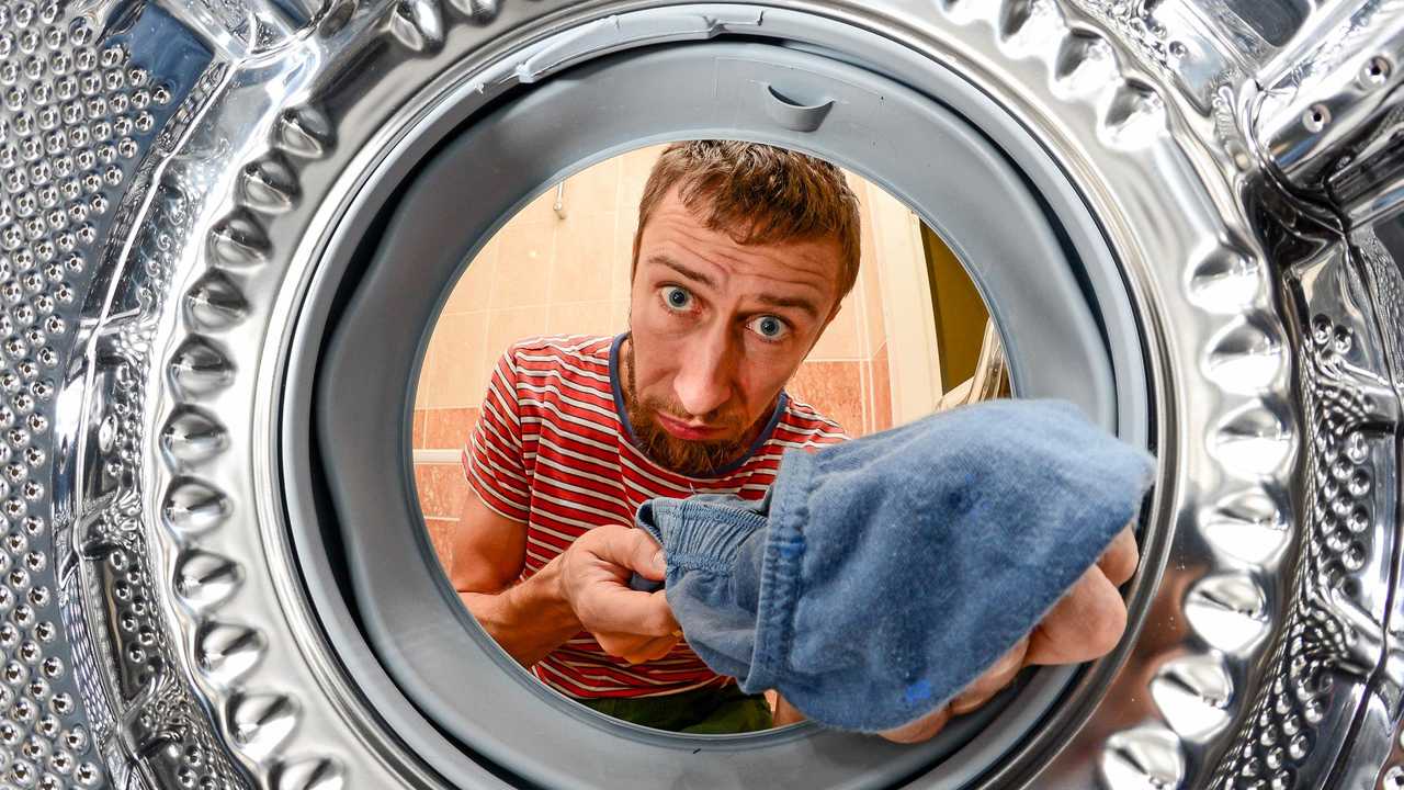 Man Doing Laundry Reaching Inside Washing Machine, inside view. Picture: Smoczyslaw