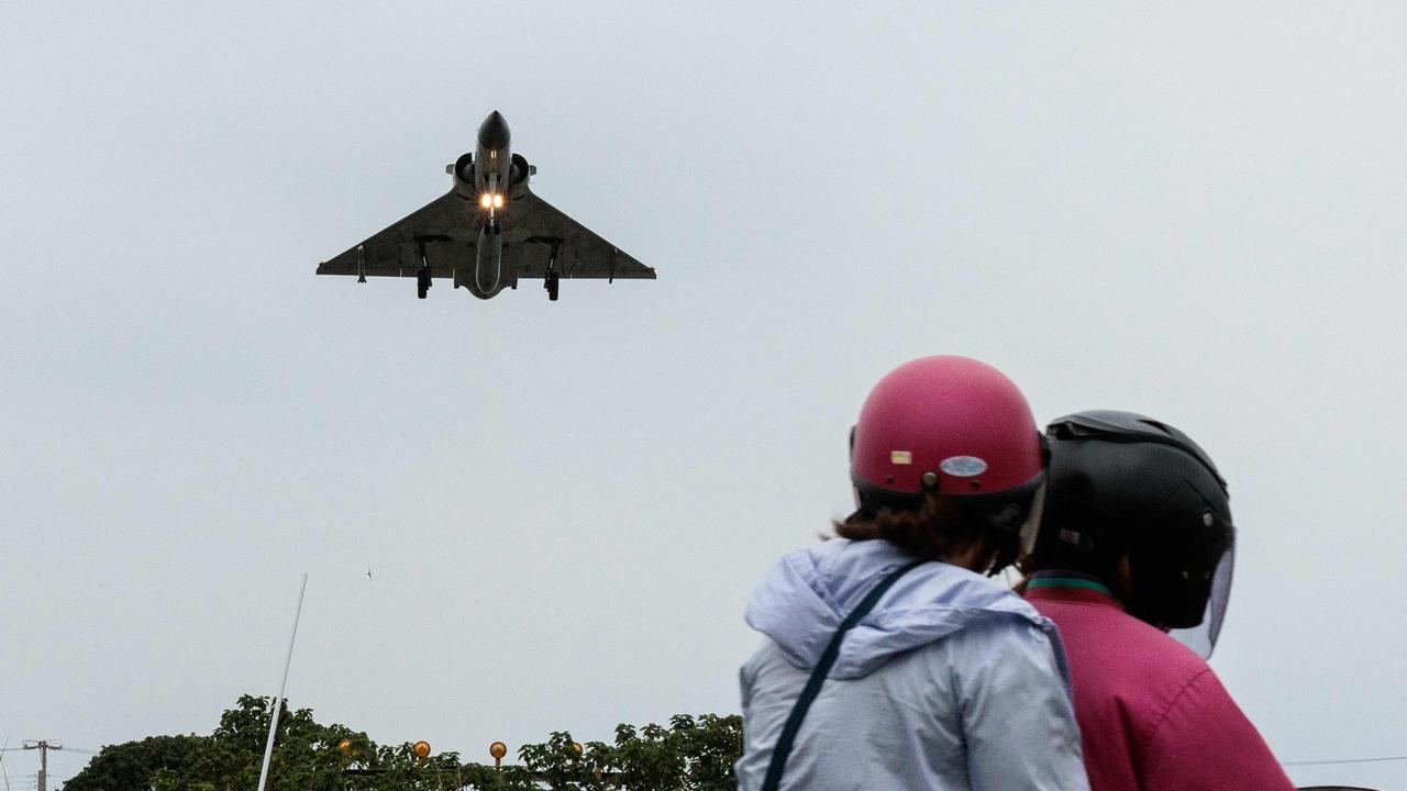 Two people ride a motorcycle as a Taiwanese Air Force Mirage 2000 fighter jet approaches for landing at an air force base in Hsinchu after China encircled Taiwan with naval vessels and military aircraft in war games exercises, in northern Taiwan on May 23, 2024.  (Photo by Yasuyoshi CHIBA / AFP)