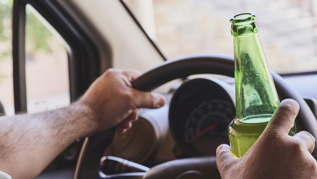 An unrecognizable man drinking beer while driving car. Concepts of driving under the influence, drunk driving or impaired driving. Drink driving generic. Picture: iSTOCK