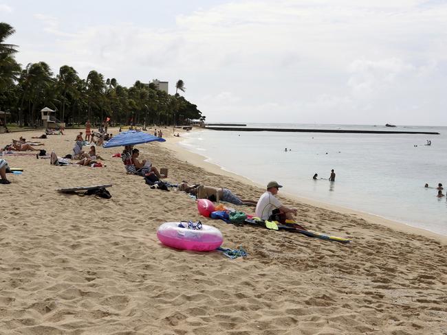 People sit on the beach and swim as Friday’s siren rings out. Picture: Caleb Jones/AP