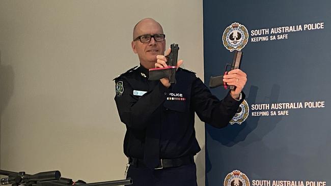 Superintendent Stephen Howard holding a real gun next to a gel blaster