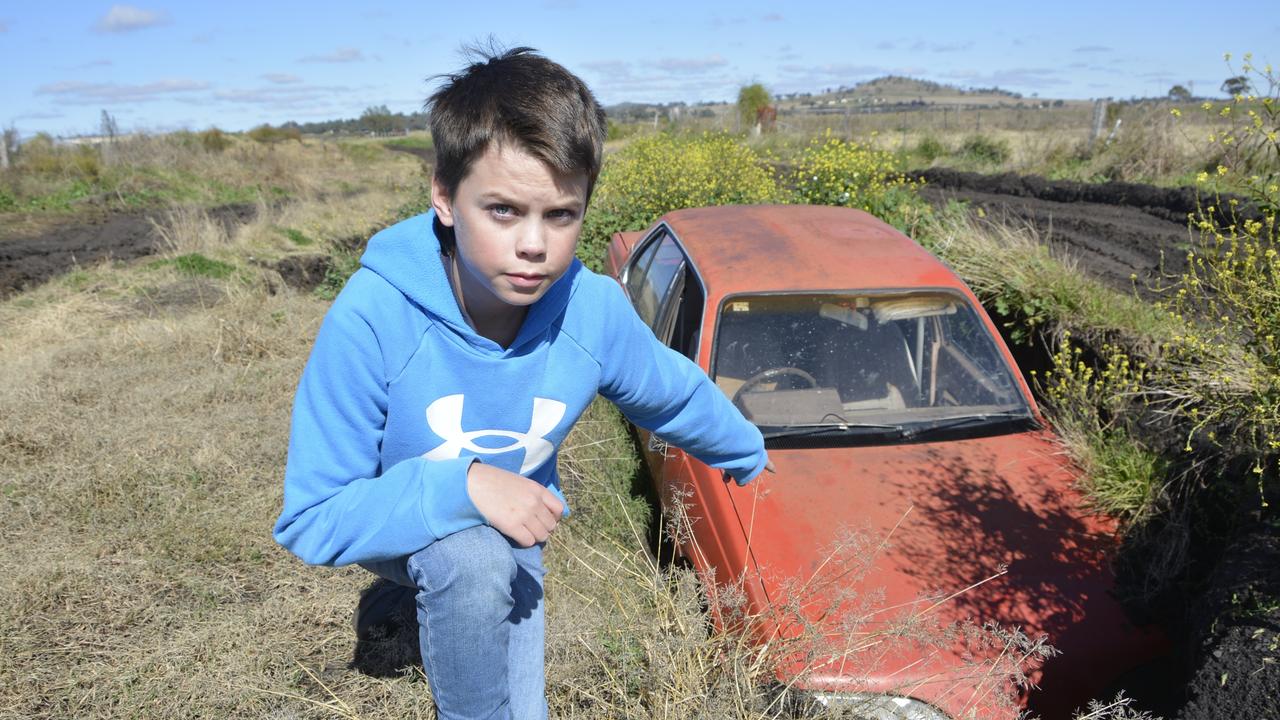 Huddson Young points to a car that became trapped while driving along Oestreich Road in Wellcamp. Residents living along it say it needs an upgrade so emergency services and other organisations can reach homes.
