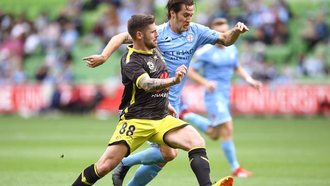 Gary Hooper of Wellington Phoenix and City’s Joshua Brillante compete for the ball.