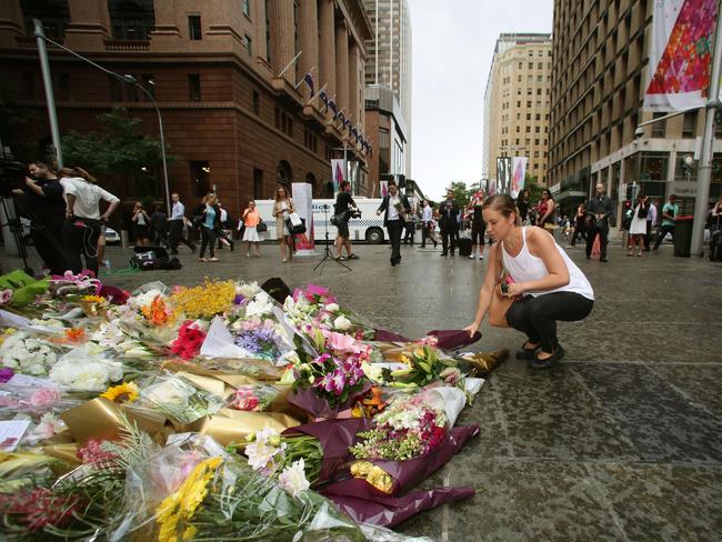 A woman places flowers at the makeshift memorial at Martin Place this morning.