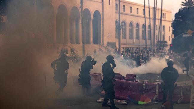 Los Angeles police officers advance on a makeshift barricade in a cloud of tear gas as clashes erupt with demonstrators next to City Hall. Picture: ETIENNE LAURENT / AFP
