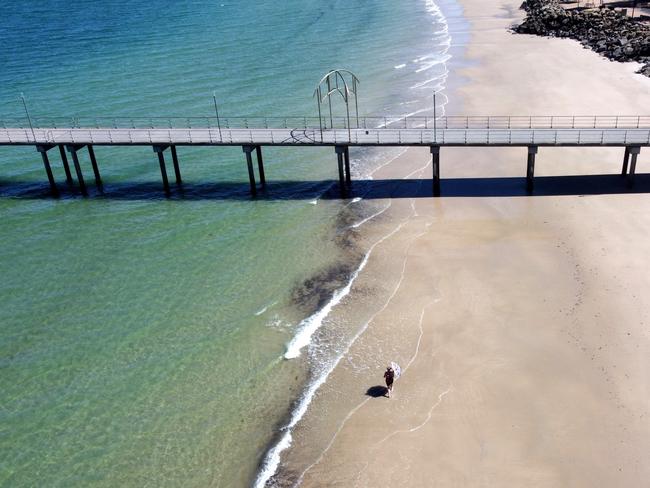 A lone woman walks along Brighton Beach. Picture: Kelly Barnes