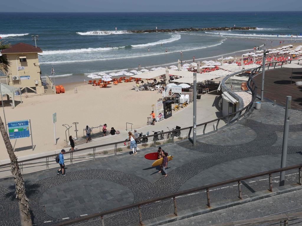 Surfers carry their boards along the beach in Tel Aviv on April 19, 2024, amid fears of a major regional spillover from the war in Gaza between Israel and Iran-backed Palestinian militants. (Photo by JACK GUEZ / AFP)