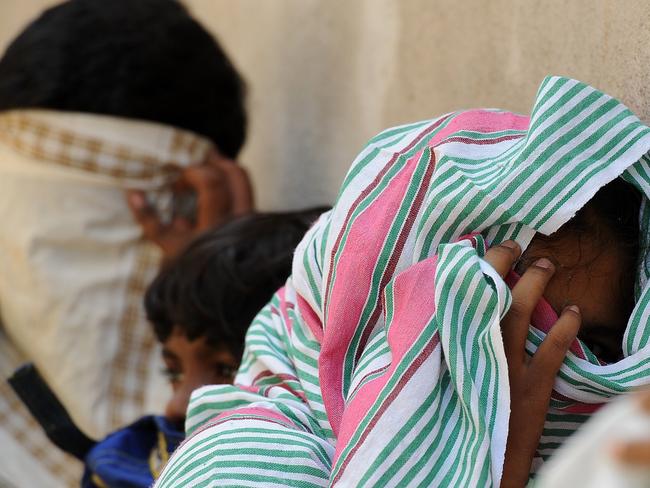 Sri Lankan asylum seekers sent back by Australia cover their faces as they prepare to enter the magistrate's court in the southern port district of Galle on July 8. Picture: Lakruwan Wanniarachchi