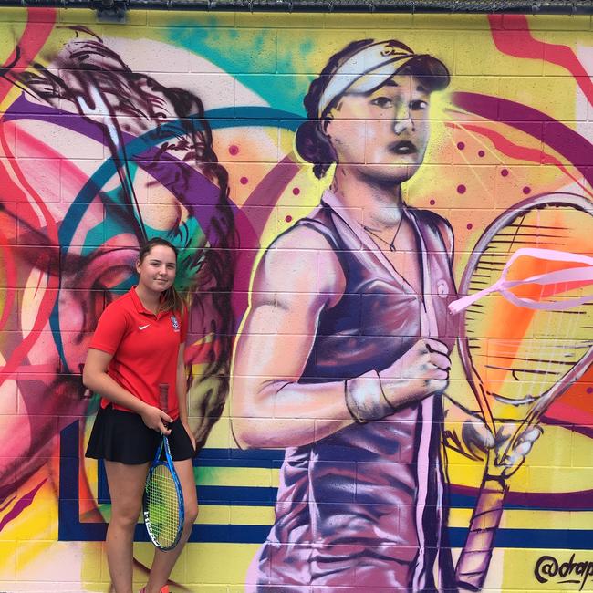 Kelvin Grove State High School tennis players Sydney Stone in front of the Ashleigh Barty mural at the Queensland Tennis Centre.