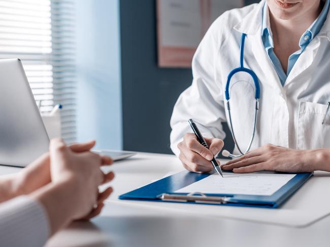 Doctor sitting at desk and writing a prescription for her patient