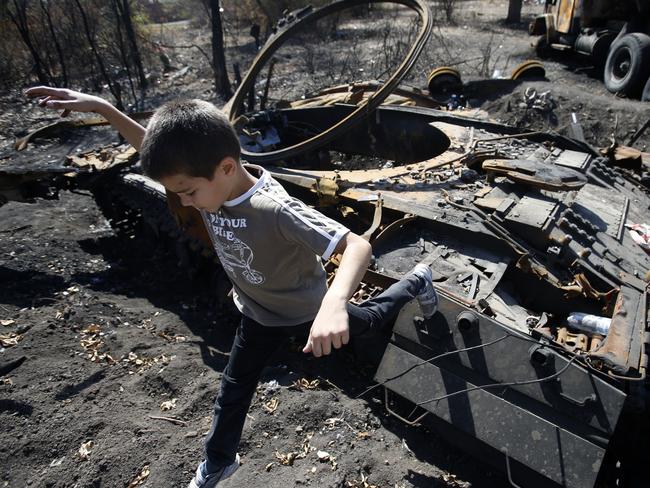 Wreckage ... a boy jumps from the remains of a charred tank in Novosvitlivka, eastern Ukraine. Picture: AP