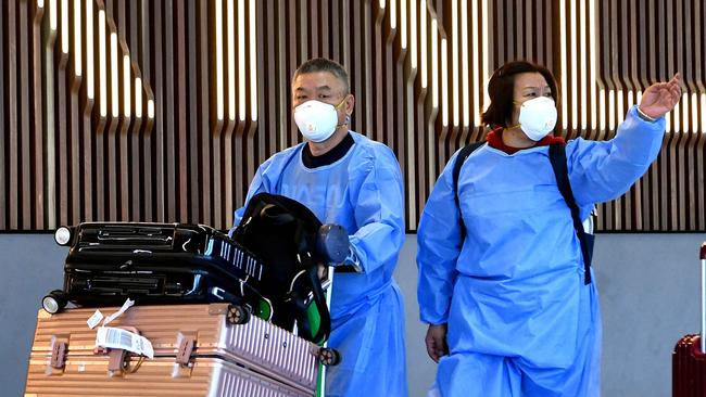 TOPSHOT - International travellers wearing personal protective equipment (PPE) arrive at Melbourne's Tullamarine Airport on November 29, 2021 as Australia records it's first cases of the Omicron variant of Covid-19. (Photo by William WEST / AFP)